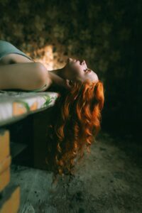 Long red  hair on woman lying on bench with her long wavy hair falling down n 
