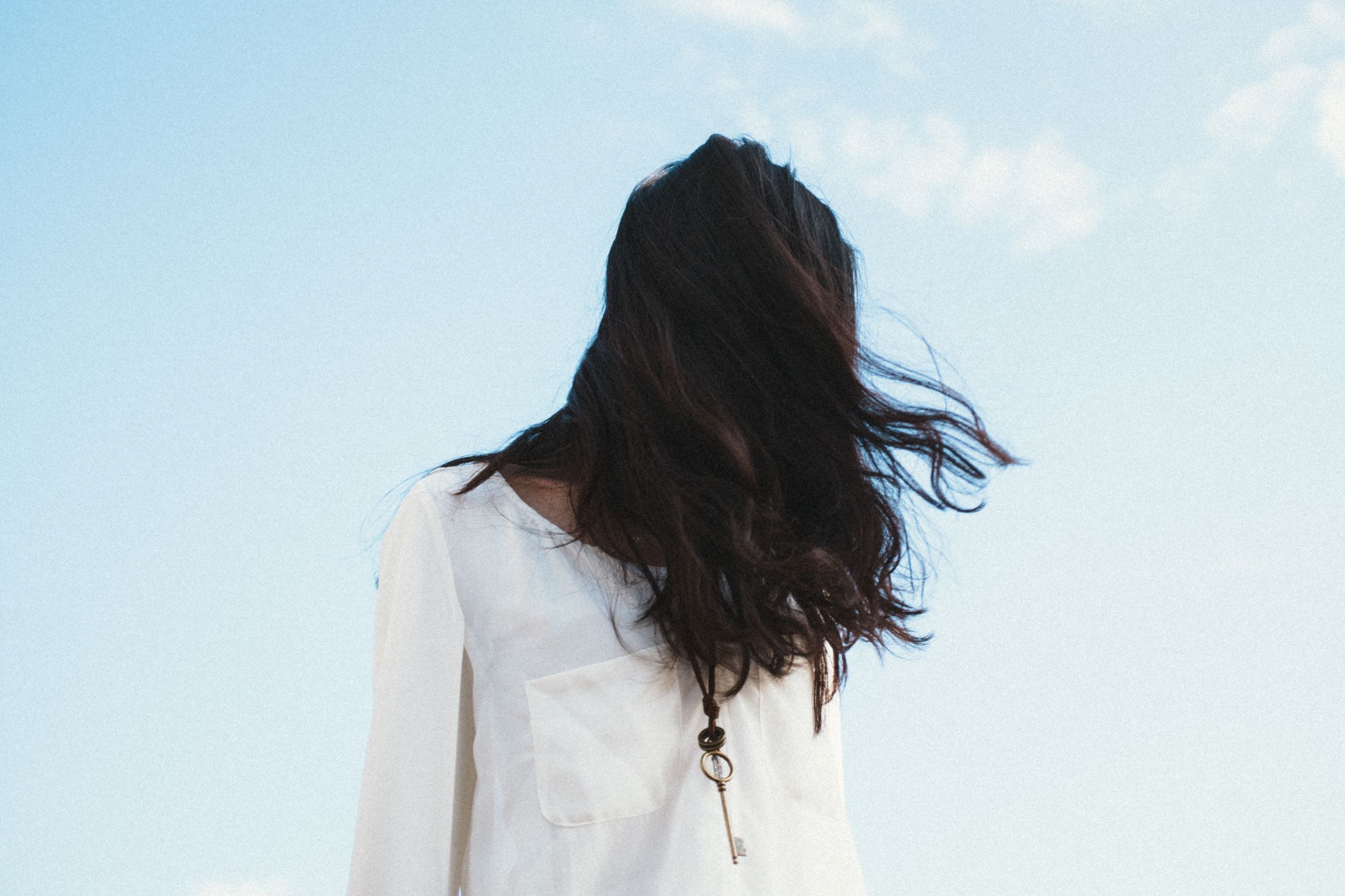 organic black hair dye, woman wearing white with long black hair hanging over her face