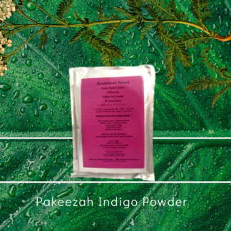 natural black hair dye product image of sealed foil packet with purple label, against a green leaf and plant background