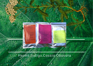 chemical free hair dye - henna, indigo and cassia obovata herbal hair colour packets displayed against a natural plant and plant root background