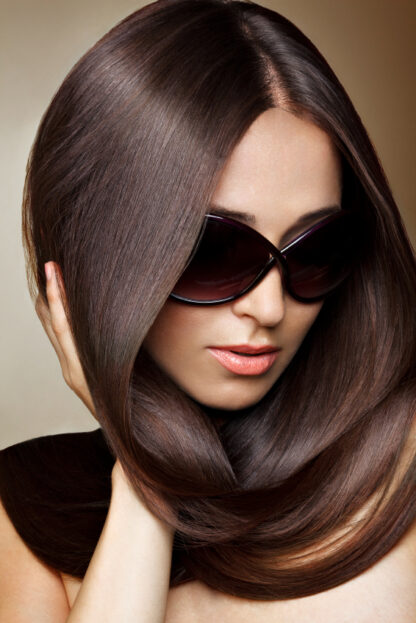 Woman wearing sunglasses with natural glossy dark brown black hair dye