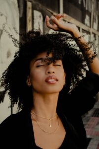 black woman with beautiful skin , eyes closed, wearing black top;customer feedback