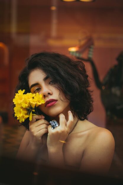 woman with short wavy bob coloured with organic brown hair dye best natural hair dye , holding a small bunch of daffodils