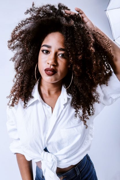 Natural hair; henna and indigo on natural afro caribbean hair; beautiful woman wearing a white shirt, with wavy, long, thick hair