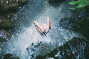 natural shampoo, picture of woman standing under a waterfall washing her hair 