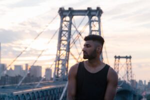 muscular asian man wearing black vest on new york bridge