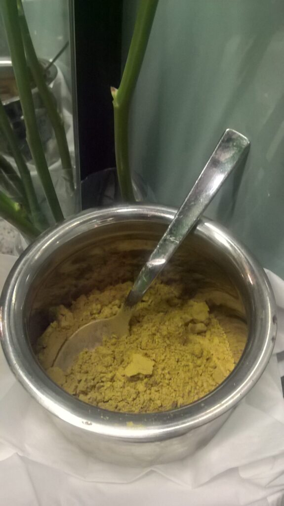 Close-up of pure henna powder in a small stainless steel dish